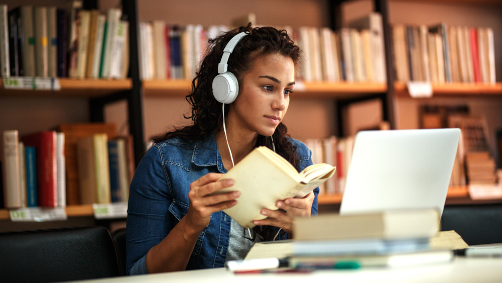 音楽を聴きながら図書館で勉強している女性
